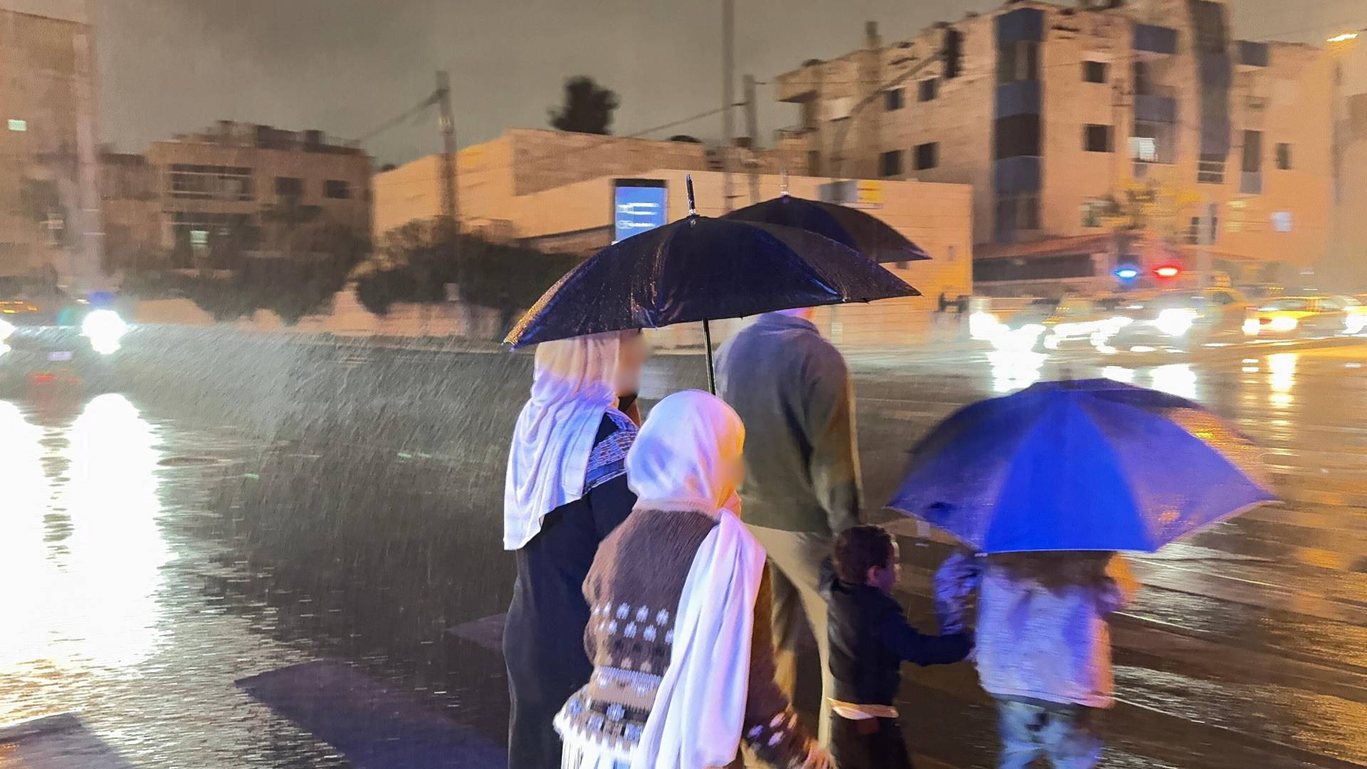 أردنيون يسيرون تحت الأمطار في عمان