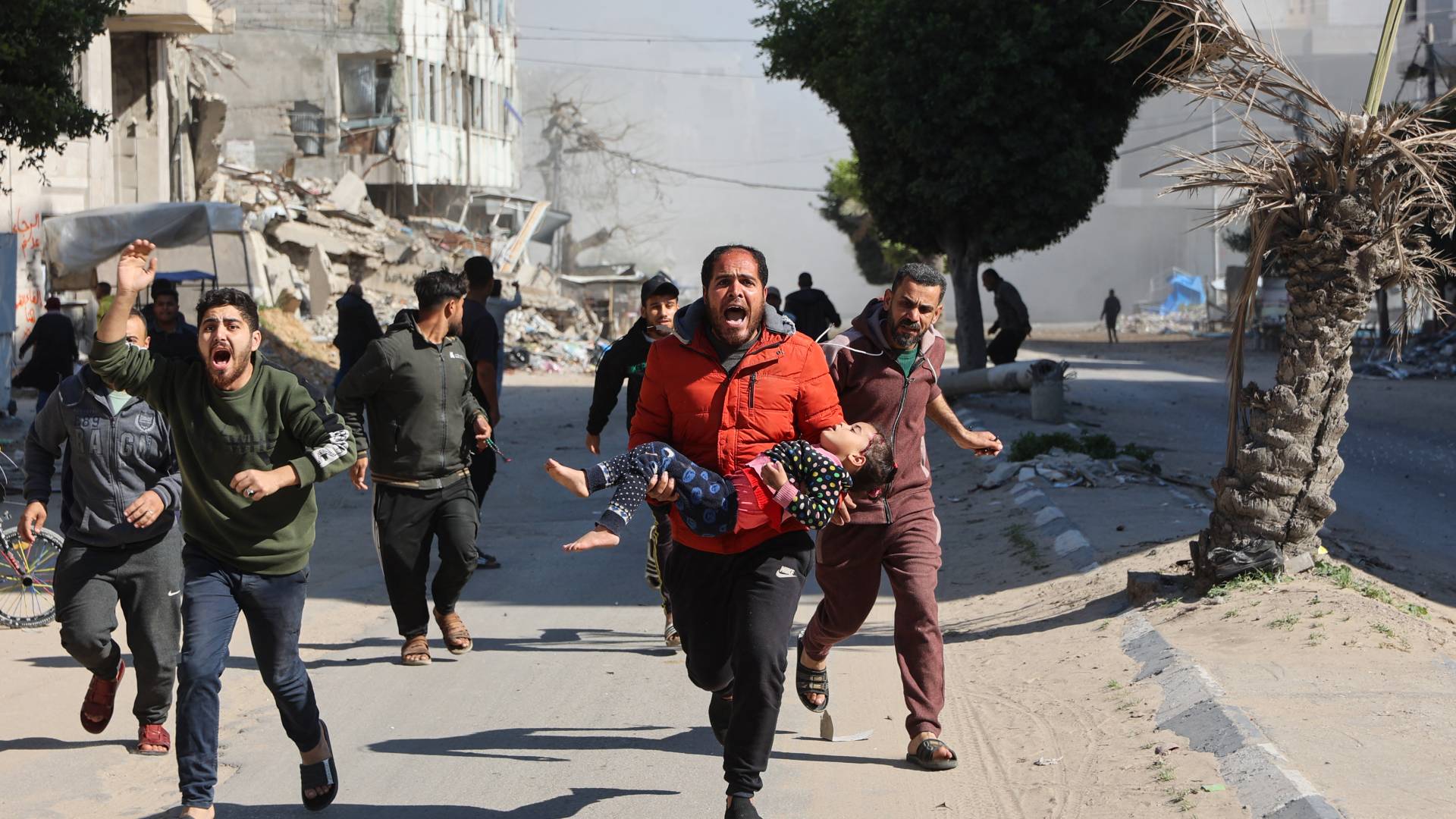 فلسطينيون يُهرعون بفتاة مصابة بعيدًا عن موقع غارات الاحتلال على مخيم نازحين مؤقت وسط مدينة غزة