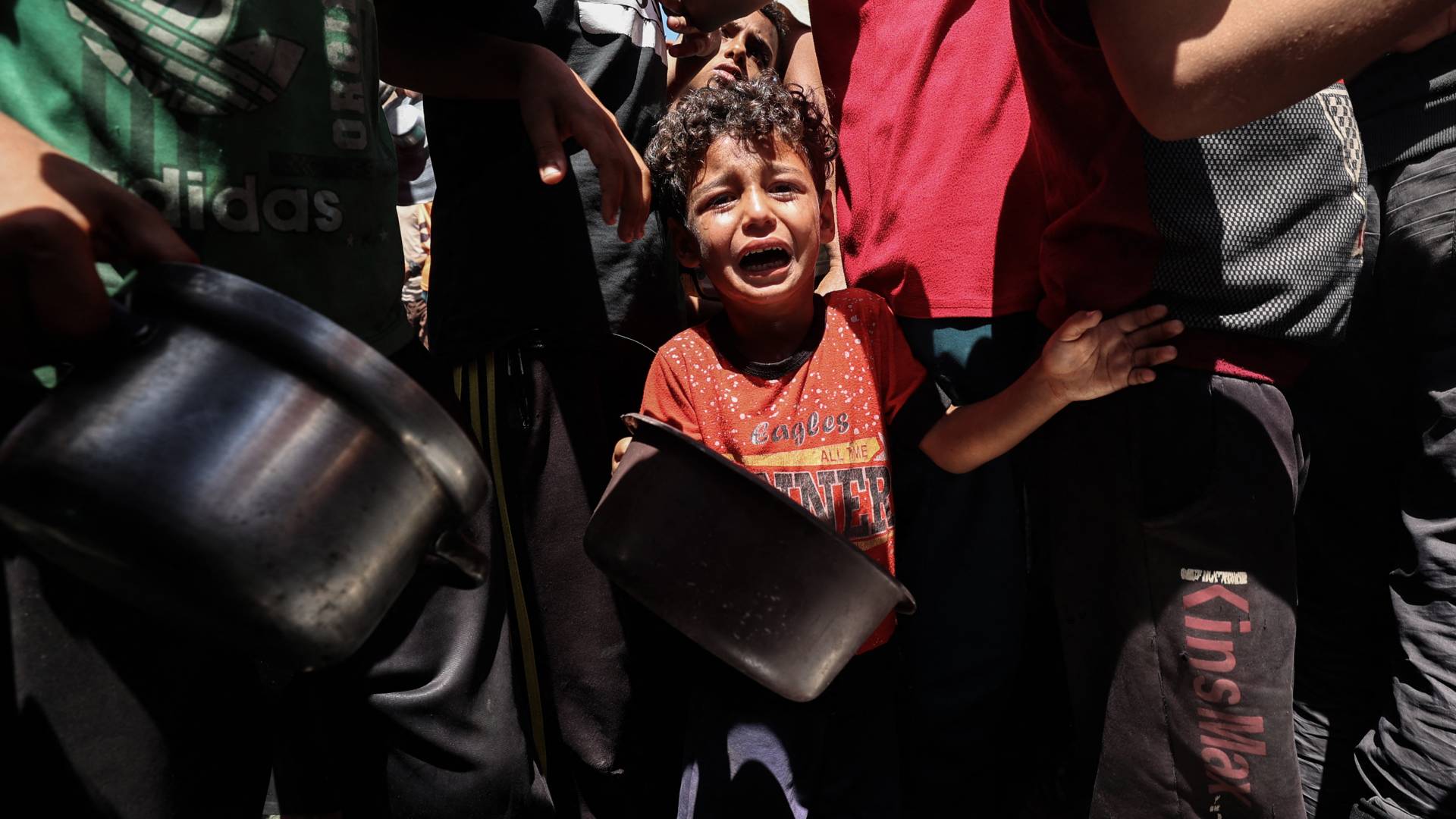 طفل من غزة يبكي خلال محاولته الحصول على الطعام