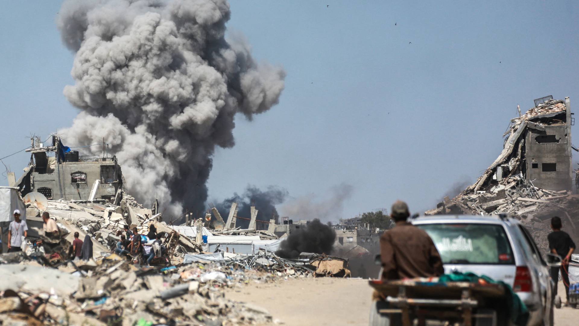 يشاهد الناس تصاعد الدخان في أعقاب غارة إسرائيلية على جباليا، شمال قطاع غزة