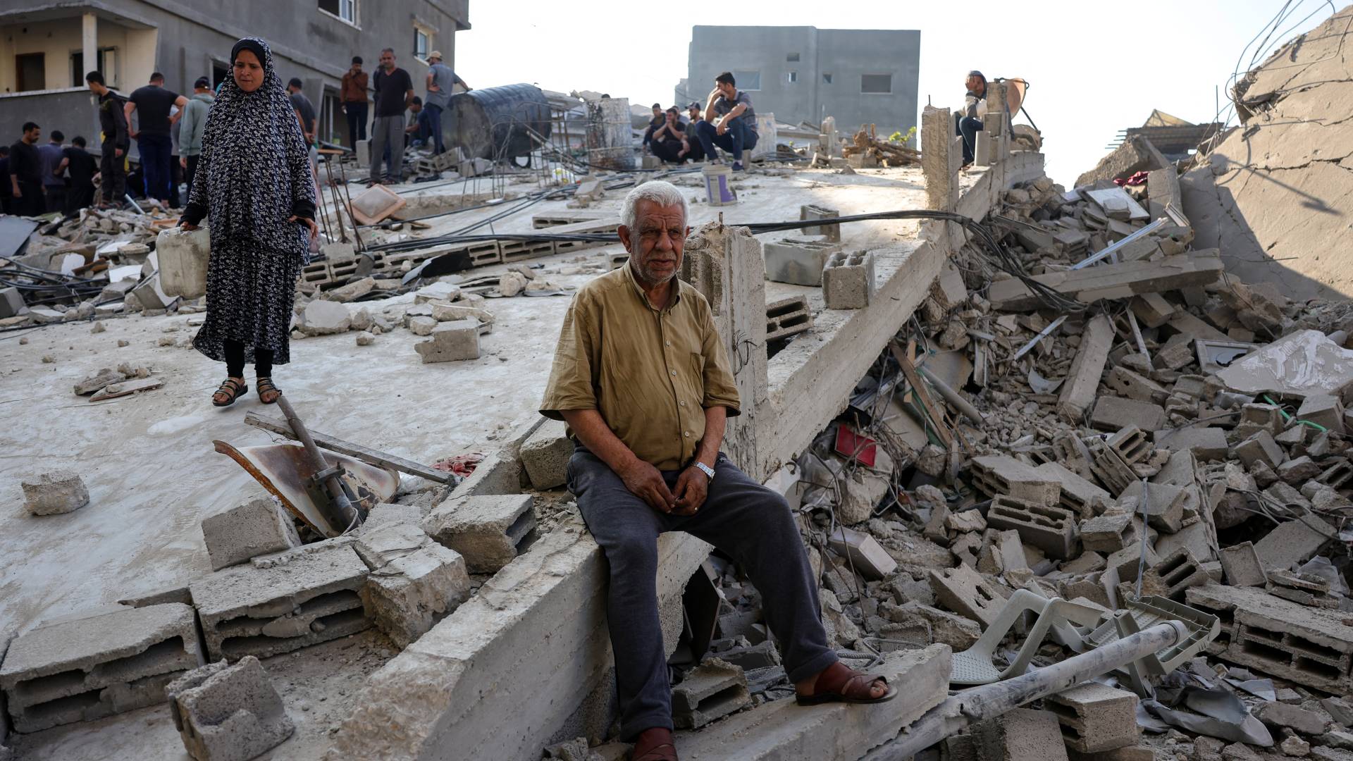 مواطنون من غزة يقفون على انقاض مباني دمرها الاحتلال