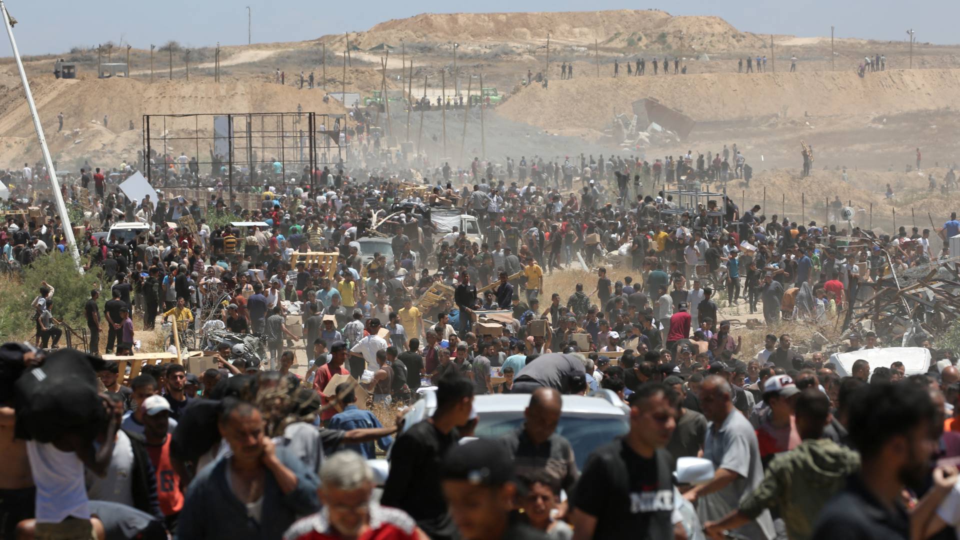 فلسطينيون نازحون يحملون مساعدات إغاثية أثناء عودتهم من مركز لتوزيع المساعدات في وسط قطاع غزة