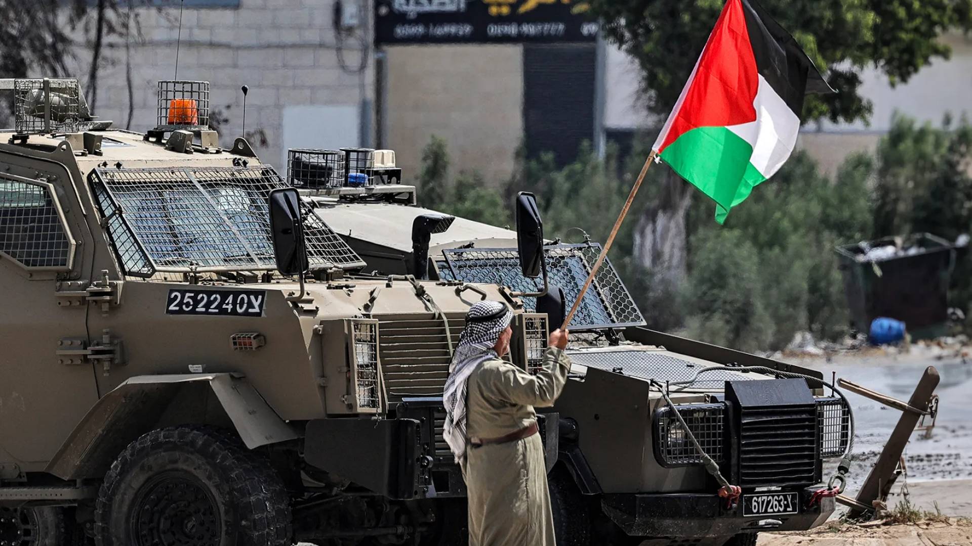 مسن فلسطيني يرفع علم بلاده أمام آليات الاحتلال في الضفة الغربية