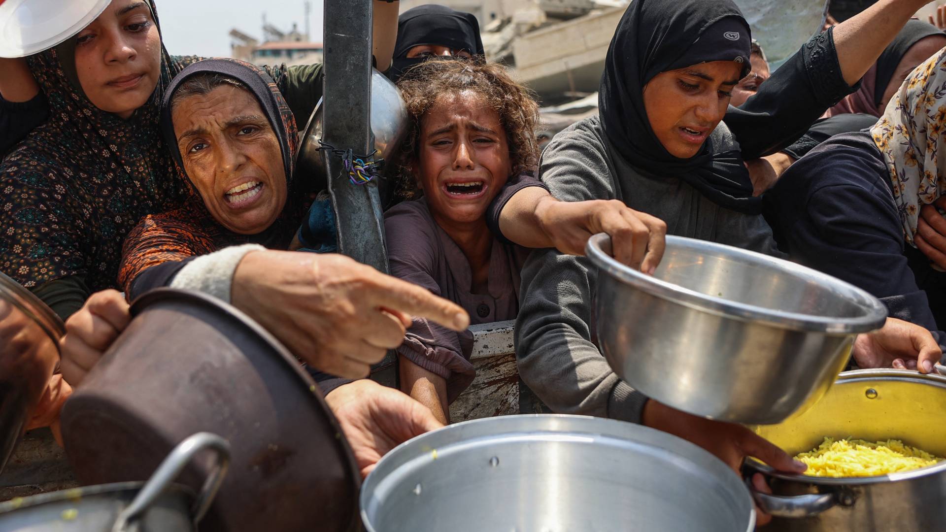 فتاة فلسطينية تبكي بينما تحاول الحصول على وجبات مطهية مع آخرين من مركز توزيع غذاء في مدينة غزة