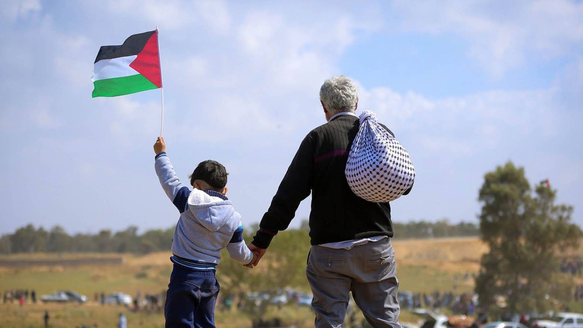فلسطيني يمسك بيد ابنه الذي يحمل علم علم فلسطين
