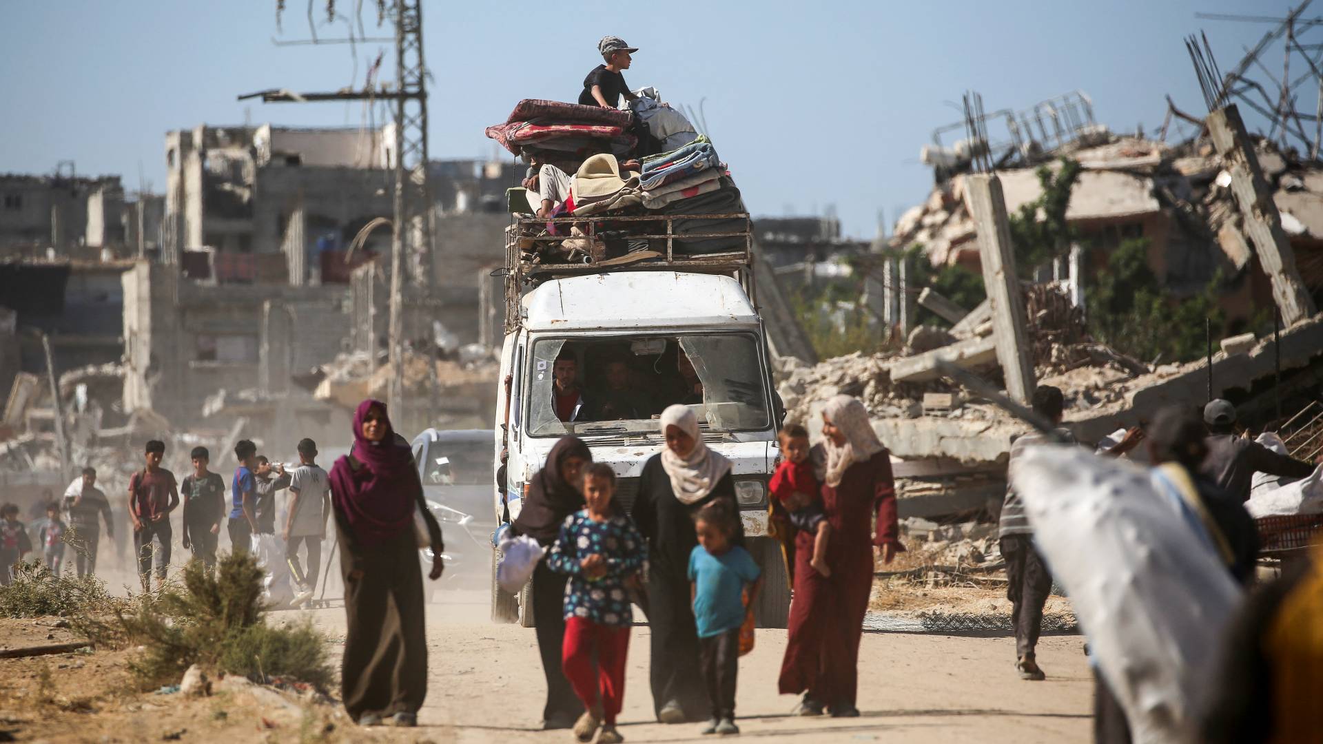 طفل يجلس فوق مركبة محملة بممتلكات الأسر أثناء عودة الفلسطينيين النازحين إلى منازلهم في منطقة الزهراء شمال مخيم النصيرات بقطاع غزة