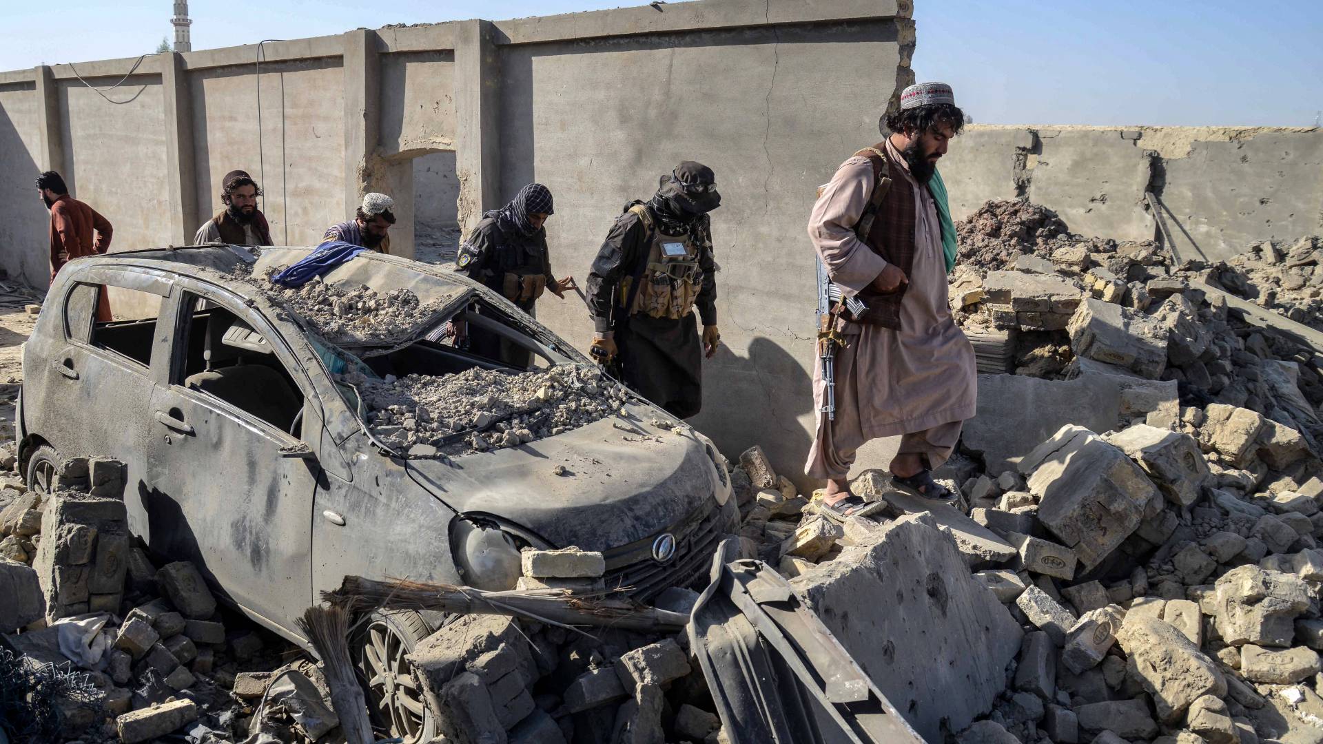 أفراد أمن من طالبان يسيرون أمام سيارة متضررة في منطقة سبين بولداك في ولاية قندهار