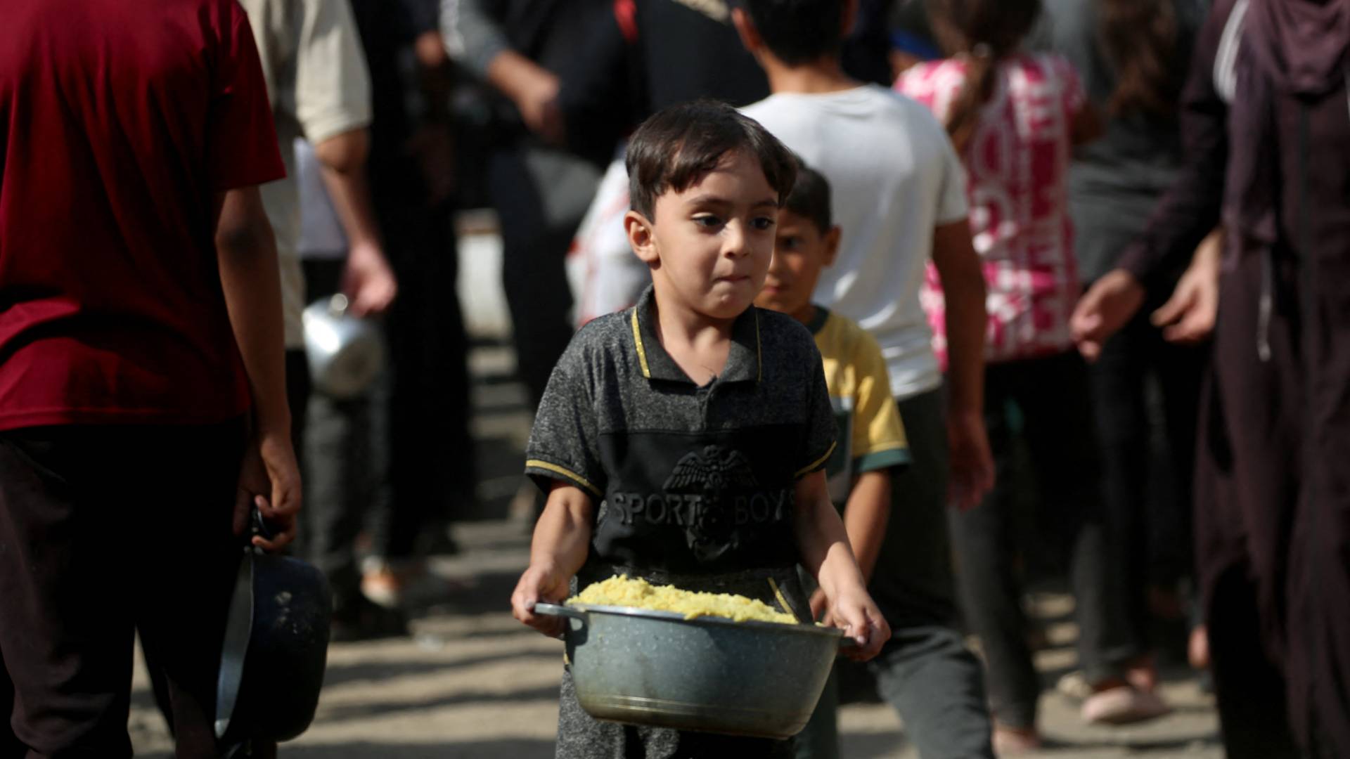 طفل غزاوي سعيد بحصوله على وجبة طعام من احد مراكز توزيع المساعدات