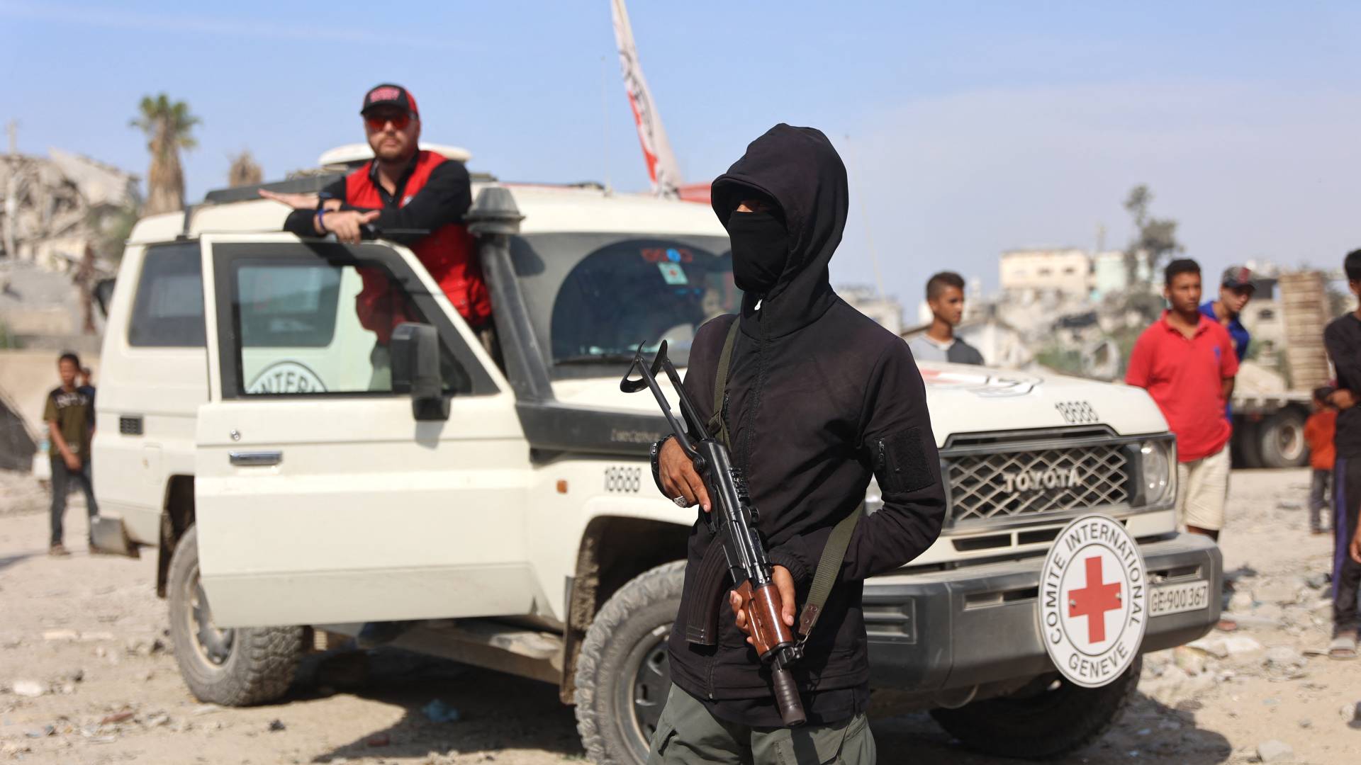 أحد عناصر كتائب القسام في غزة تظهؤ خلفه إحدى مركبات الصليب الأحمر الدولي