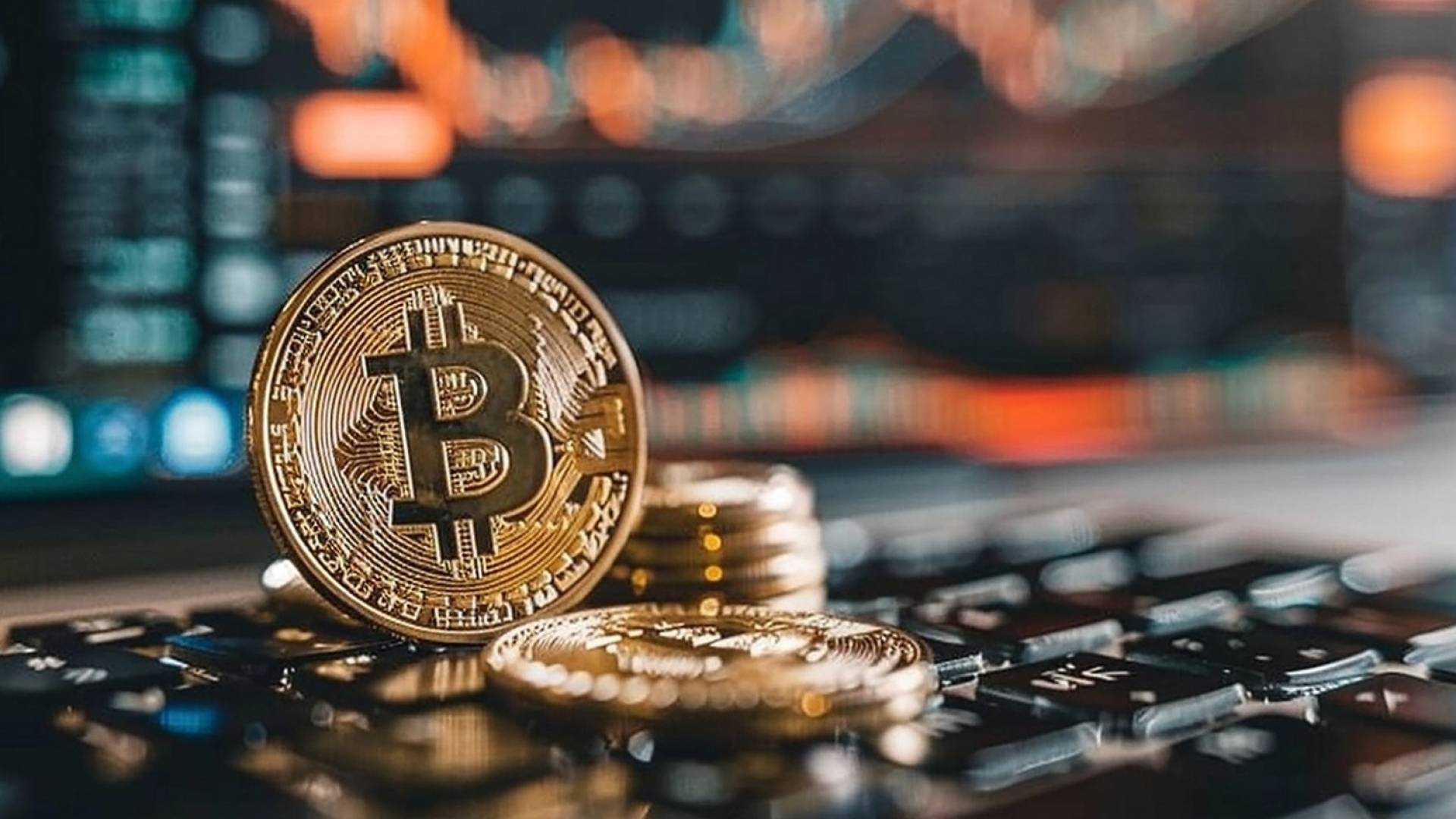 عملة البيتكوين المعدنية باللون الذهبي، تتوسطها علامة ₿ البارزة، مع خلفية رقمية توحي بعالم التكنولوجيا والأسواق المالية