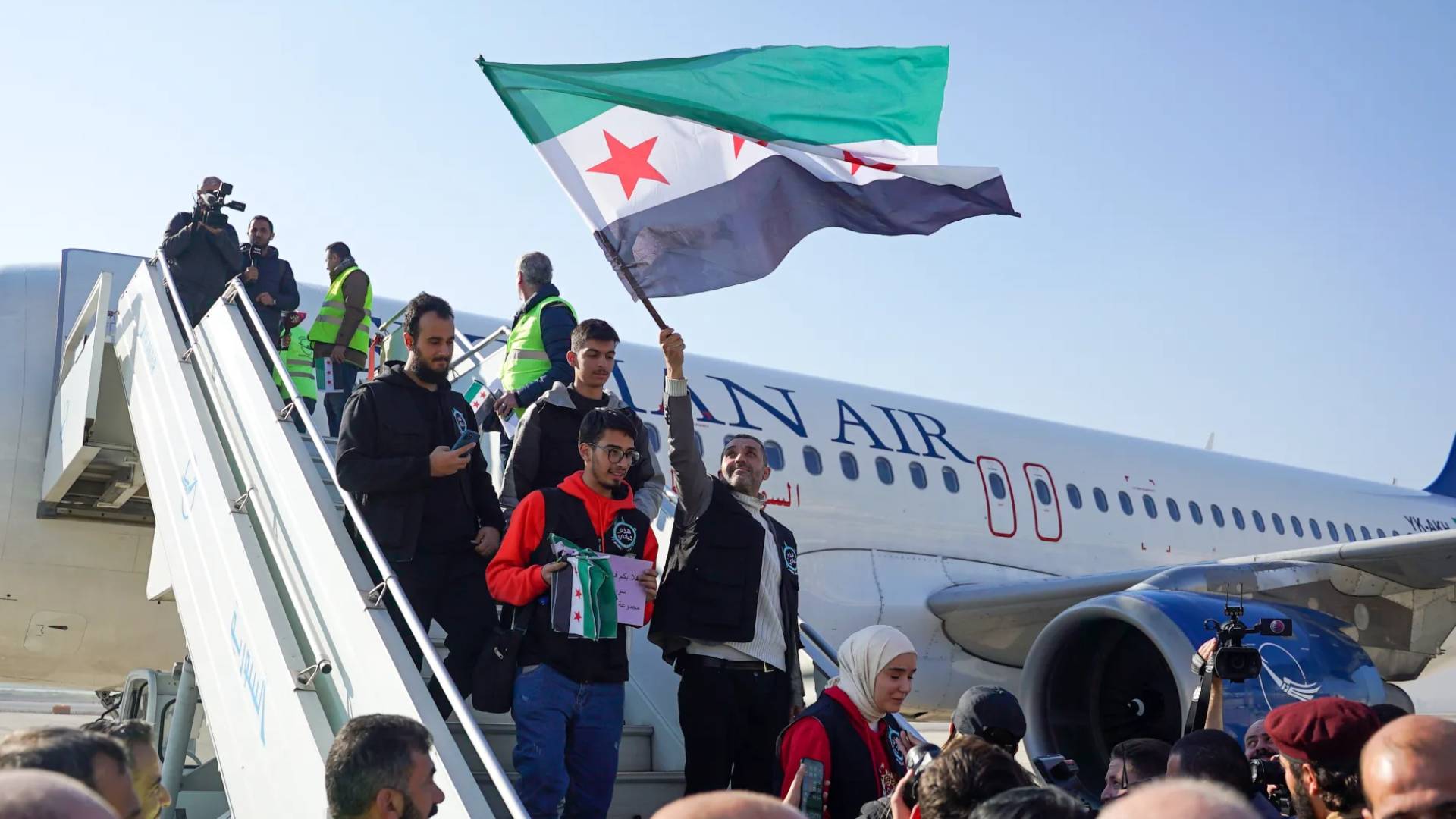 مواطنين سوريين يحملون علم سوريا الجديد
